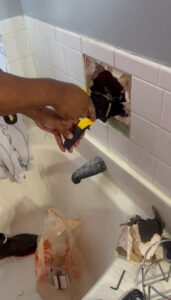 Aquaflame Restores It technician repairing a leaking pipe inside a bathroom wall in an Atlanta home to prevent hidden water damage